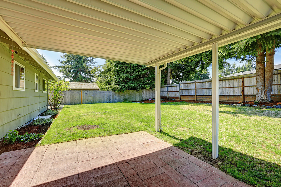 covered concrete patio and grassy backyard