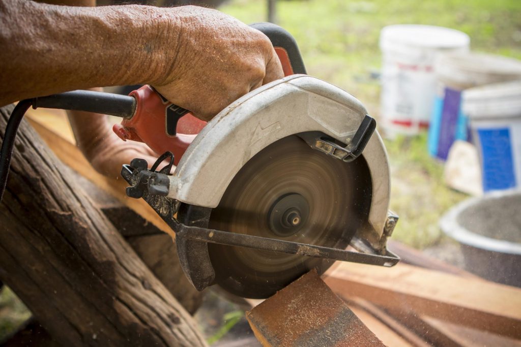 man cutting up pieces of woods using an electrical saw