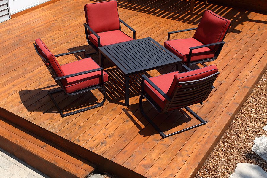 little elevated wood deck with red chairs and a table